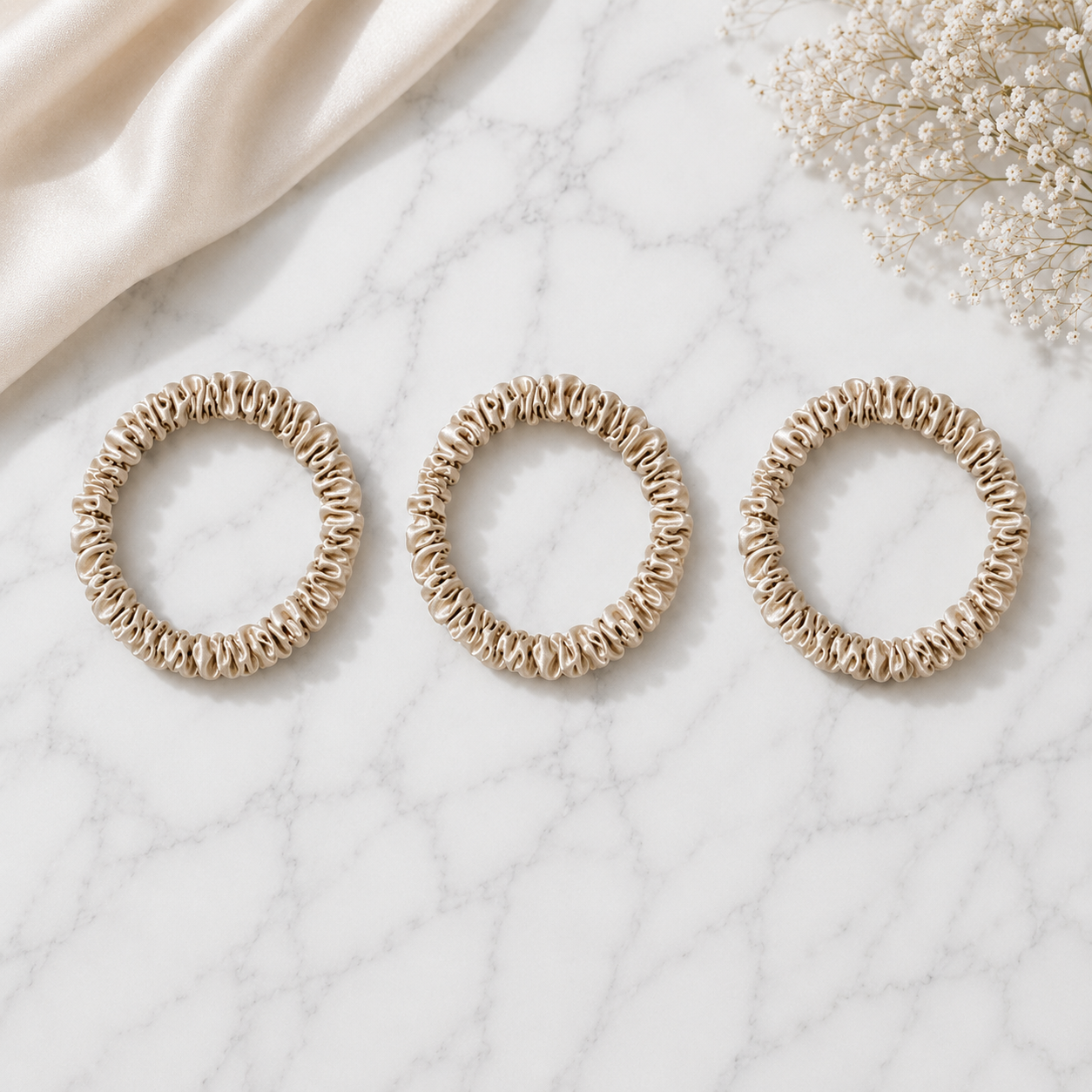 Champagne 22 momme silk scrunchies arranged on a marble surface