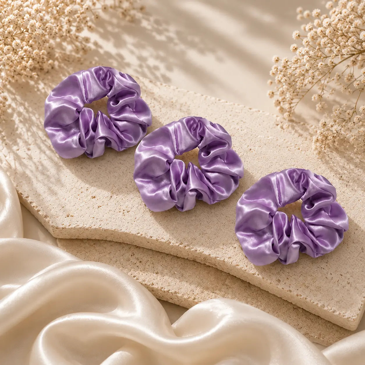 Champagne 22 momme silk classic lilac scrunchies arranged on a marble surface