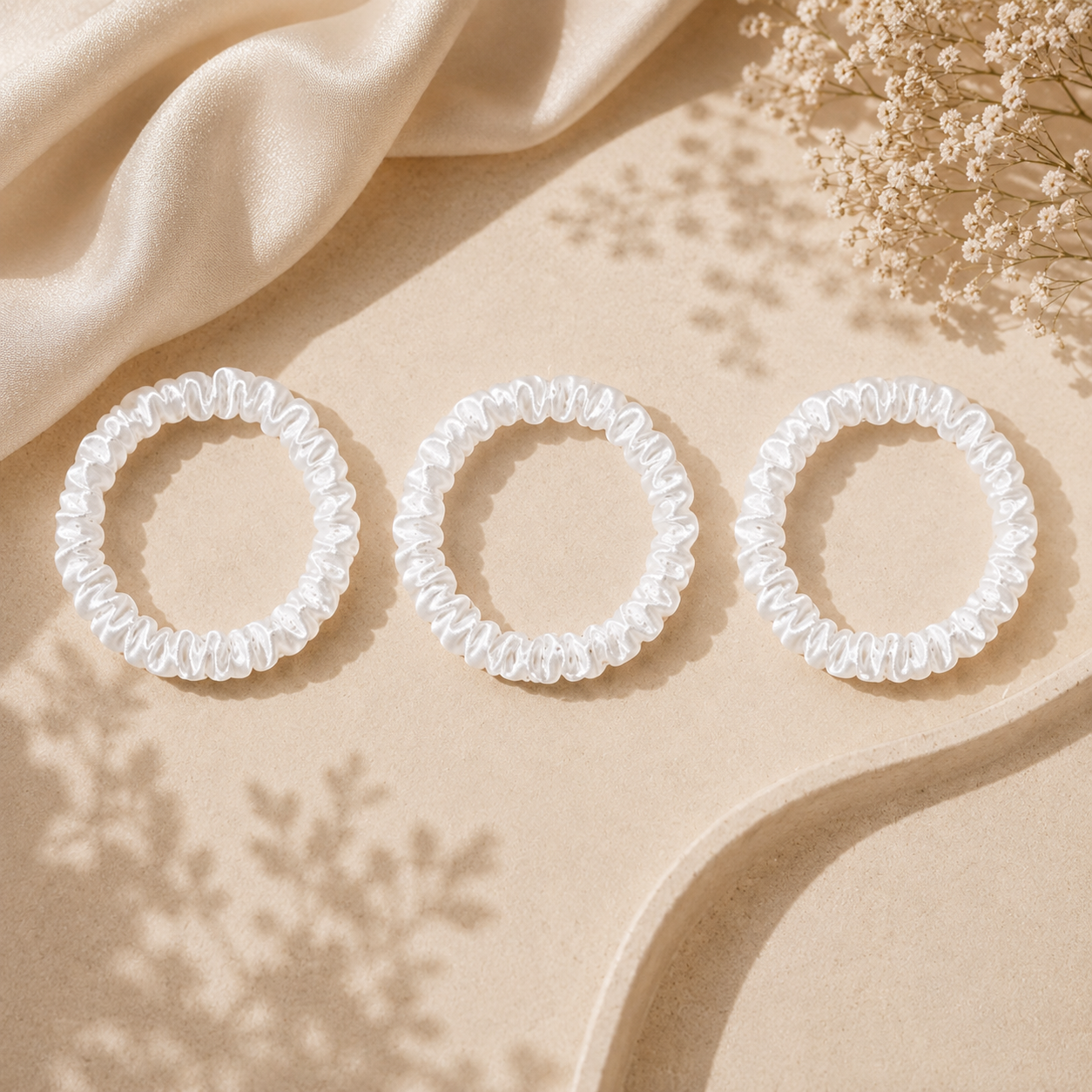 Luxury silk white scrunchies displayed on a soft satin background