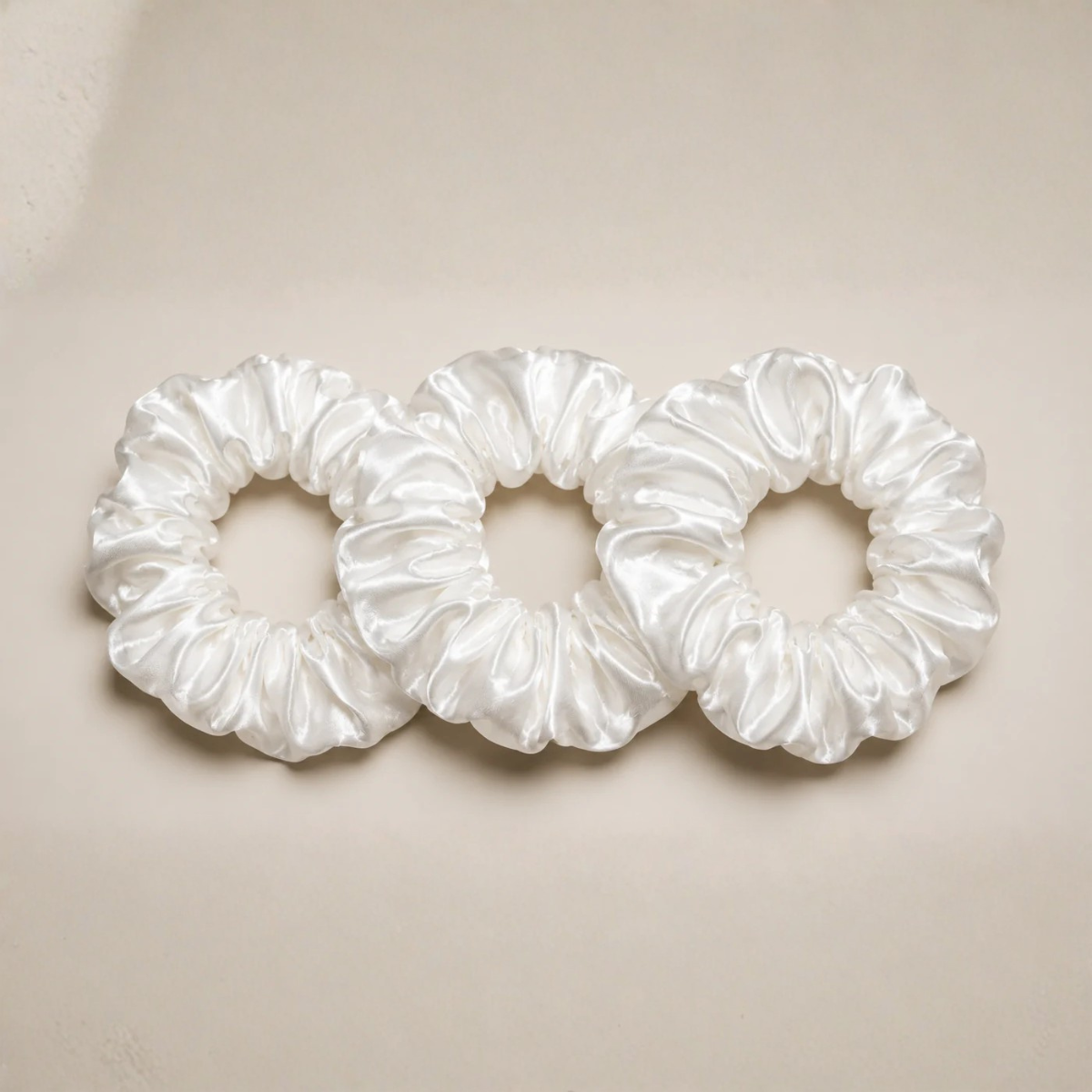 Champagne 22 momme silk classic white scrunchies arranged on a marble surface