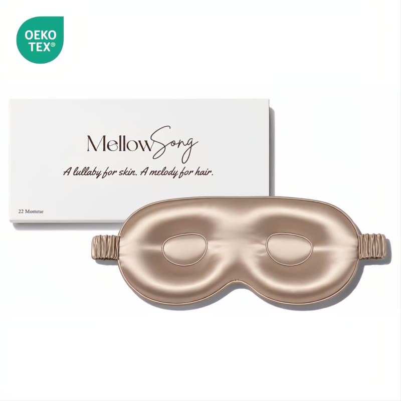 Champagne gold contoured silk eye mask by Mellow Song, shown with its original white packaging box and an OEKO-TEX logo on a plain white background.