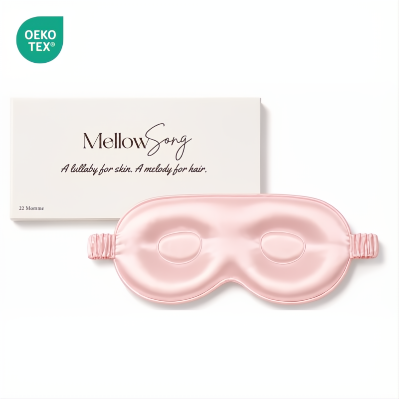 Light pink contoured silk eye mask by Mellow Song, shown with its original white gift box and an OEKO-TEX logo on a plain white background.