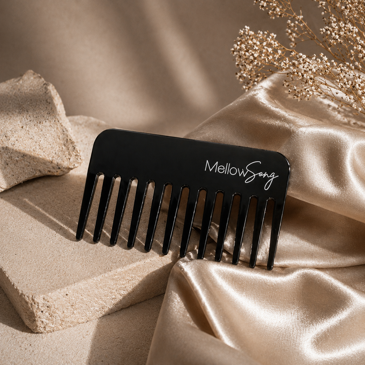 Black comb with 'Mellow Song' branding on a beige fabric background