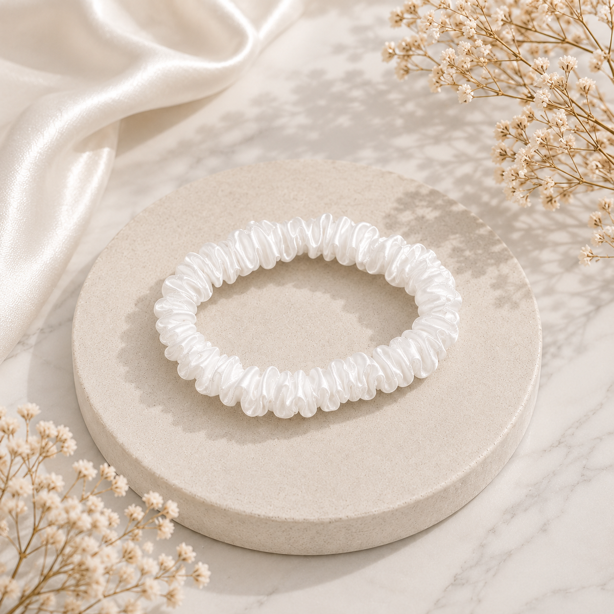 Champagne 22 momme silk white scrunchie arranged on a marble surface