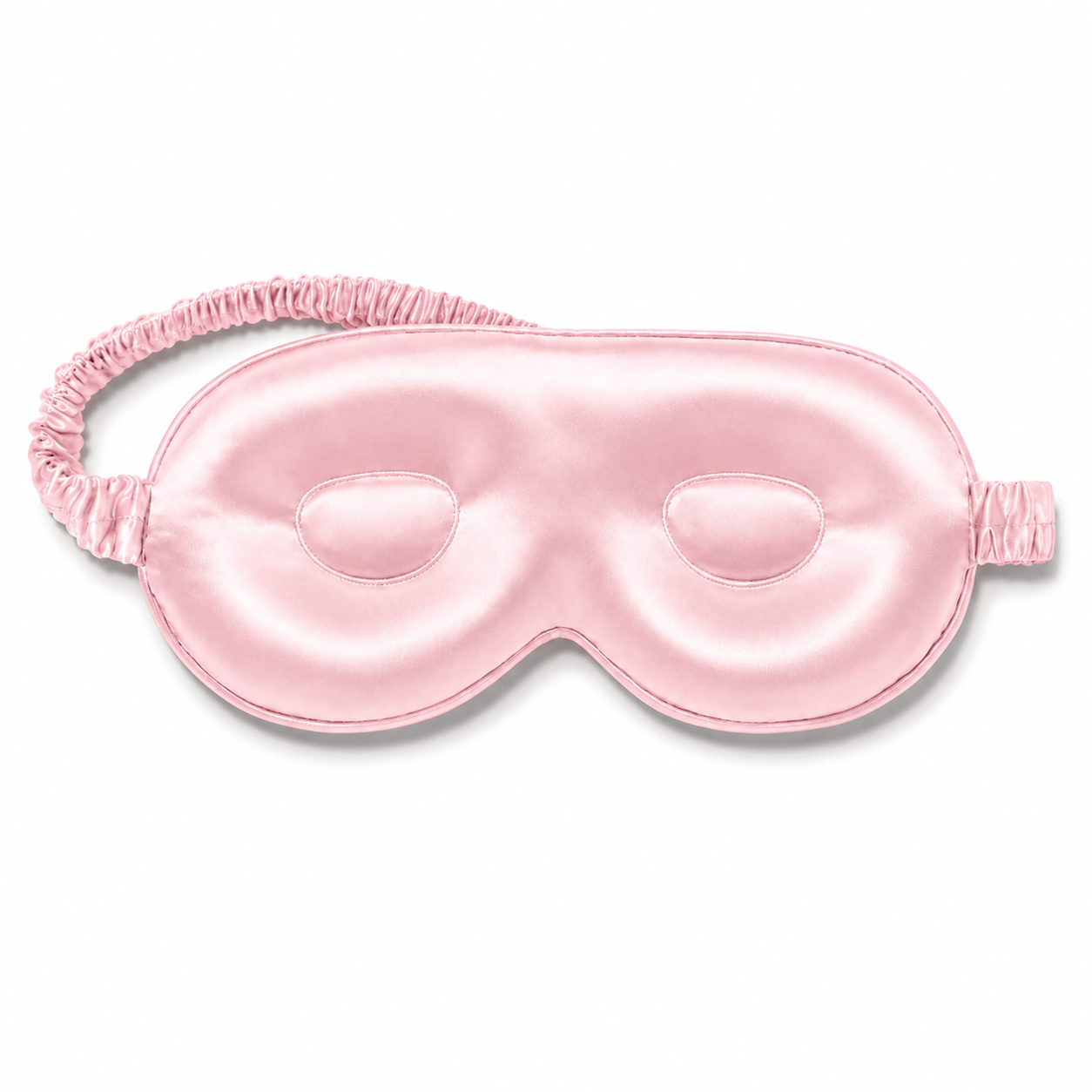 Light pink contoured silk sleep mask with a matching ruched elastic strap, isolated on a plain white background.