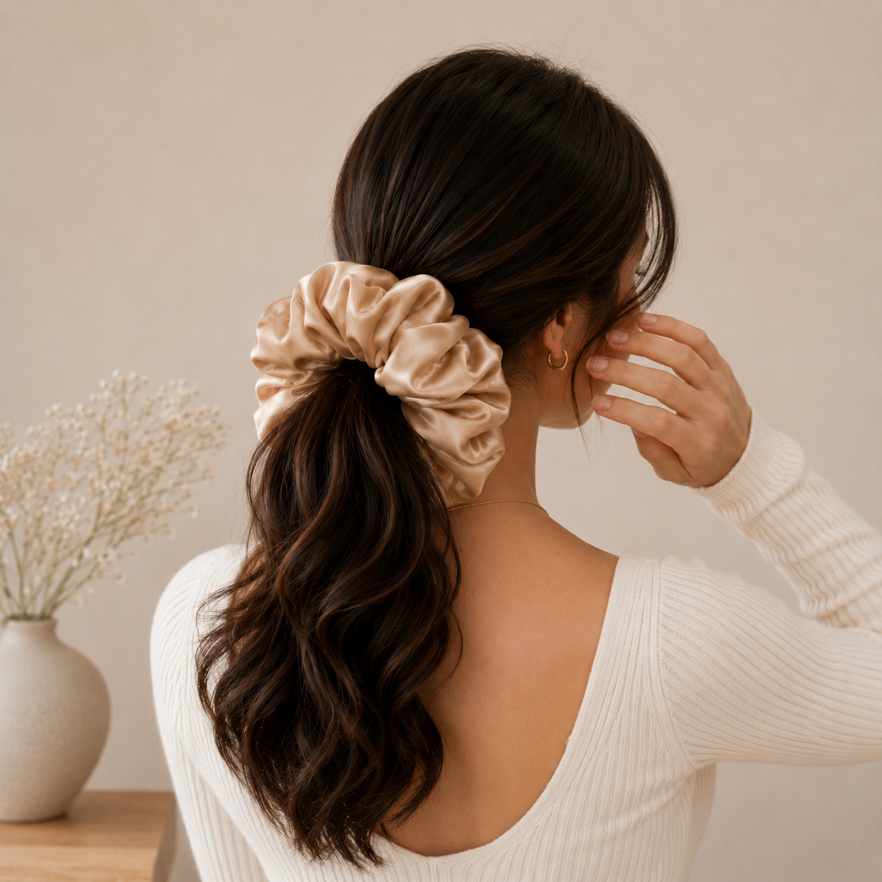 Woman wearing a beige silk grand scrunchie in a low ponytail hairstyle