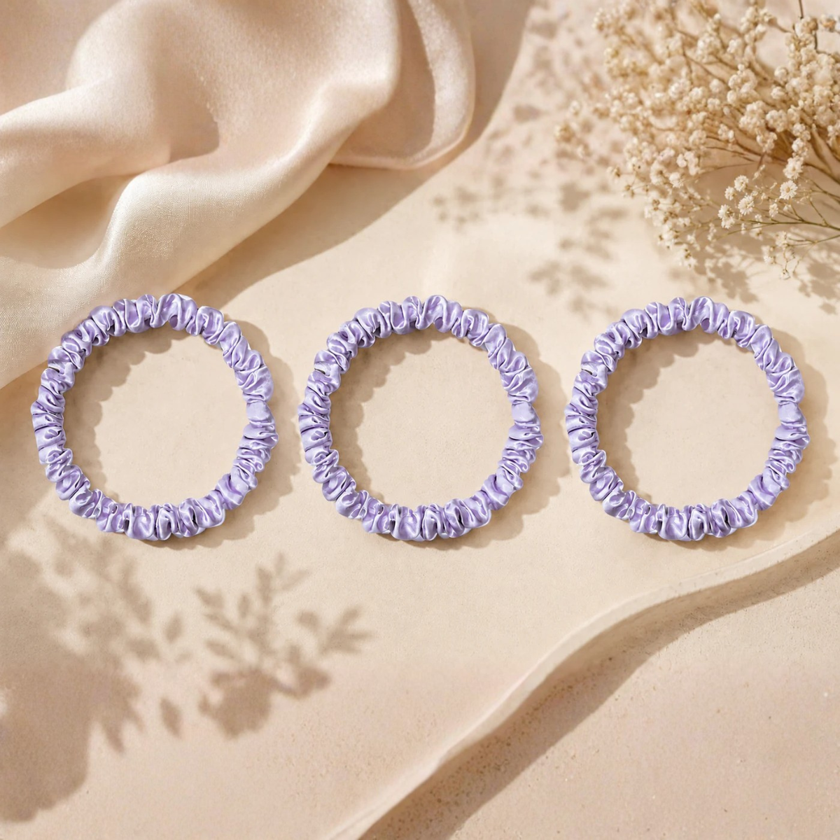 Luxury silk lilac scrunchies displayed on a soft satin background